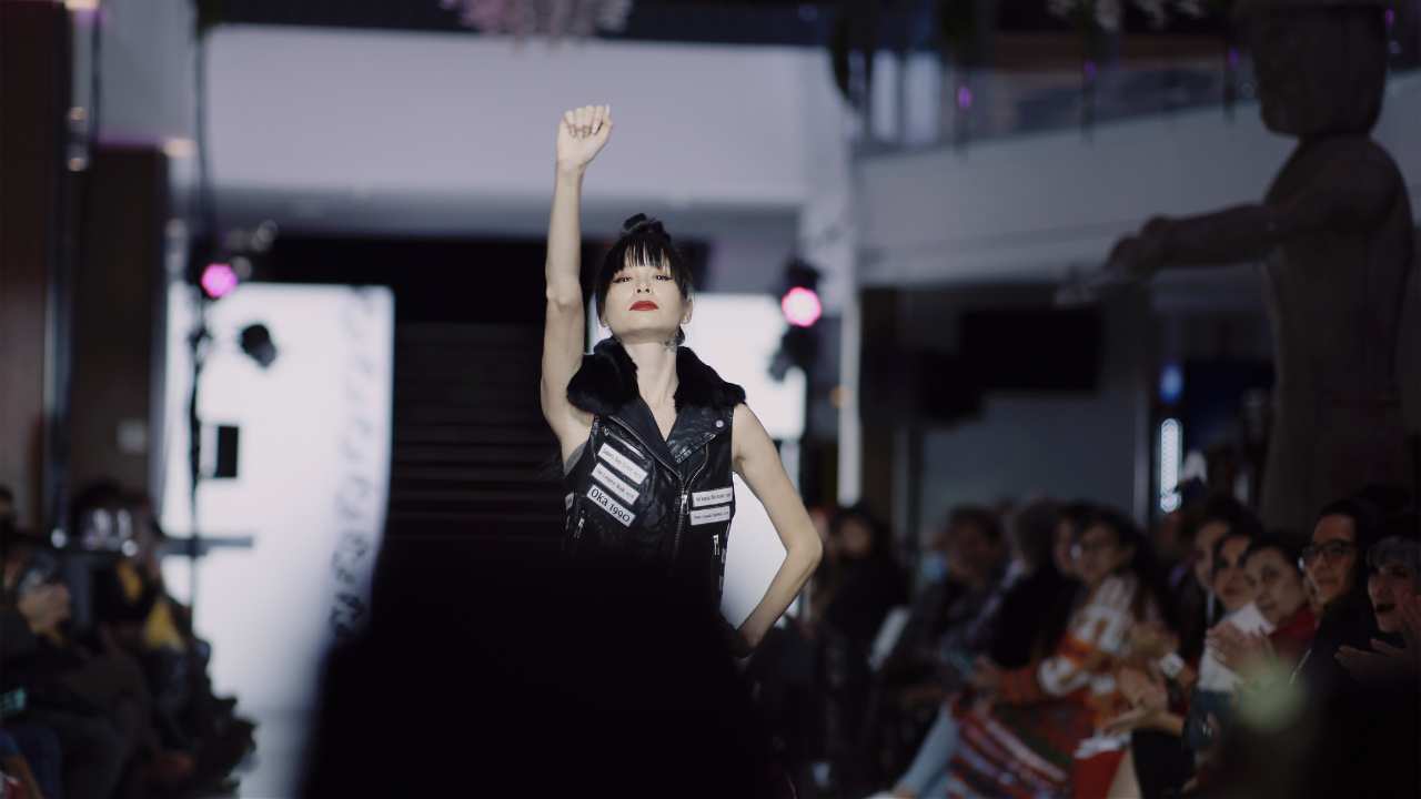 a woman on a runway with one arm in the air